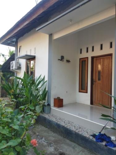 een klein wit huis met een houten deur bij Pakok homestay in Kuta Lombok