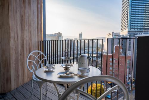 a table and chairs on a balcony with a view of a city at Randor Hotel Hiroshima Prestige in Hiroshima