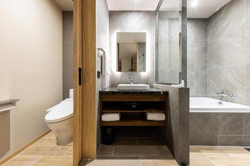 a bathroom with a sink and a toilet and a tub at Solaria Nishitetsu Hotel Taipei Ximen in Taipei