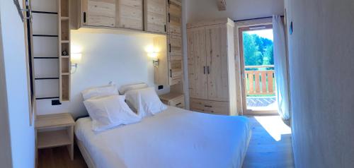 um quarto com uma cama branca e uma varanda em Superbe Chalet à Megève 7 pers Près des Pistes em Demi-Quartier