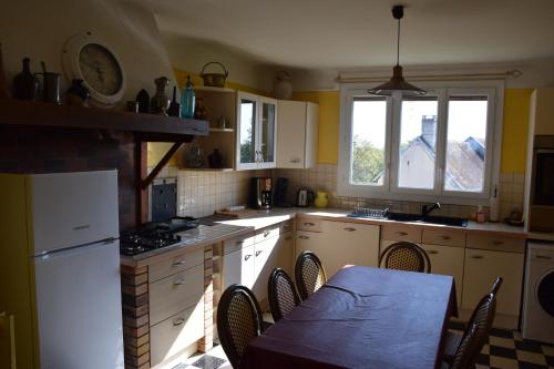 une cuisine avec des armoires blanches et une table avec des chaises dans l'établissement Logement authentique à proximité de Sancerre, à Sainte-Gemme