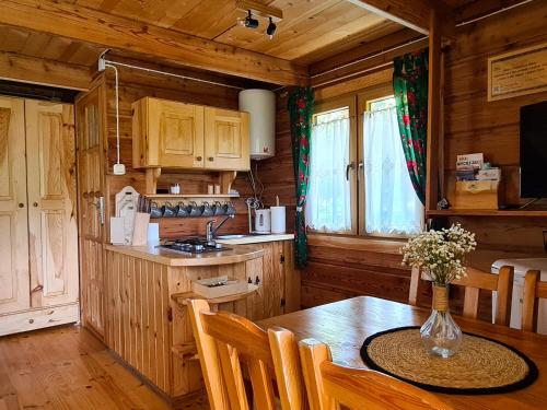 a kitchen with a table with a vase of flowers on it at Domki Pod Horbem in Polańczyk