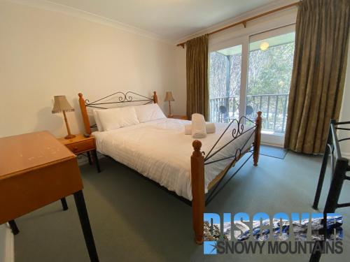 a bedroom with a bed and a large window at Three Bears 2 in Thredbo