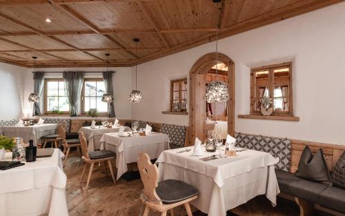 un restaurant avec des tables et des chaises blanches et des plafonds en bois dans l'établissement Hotel Kassian, à Lagundo