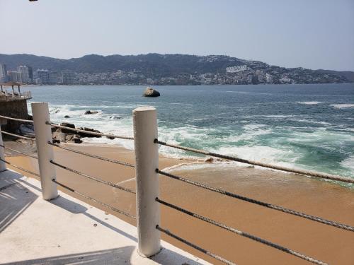 a fence on a beach with the ocean at PH Torres Gemelas in Acapulco