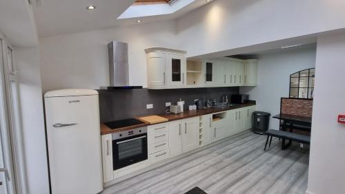 a kitchen with white cabinets and a refrigerator at Stylish Suites with kitchenette in London Colney