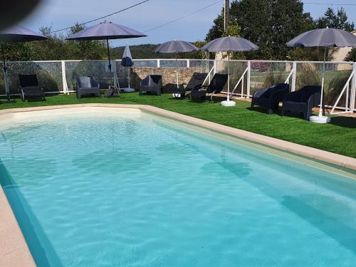 une piscine avec chaises et parasols dans l'établissement Le Hameau des Cardenals, à Salviac