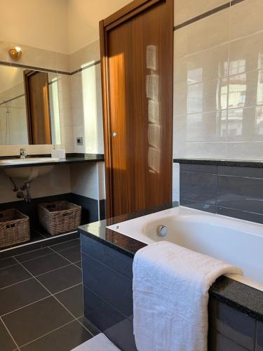 een badkamer met een bad, een wastafel en een spiegel bij Gavirate Cozy Apartment BBQ/Garden in Gavirate