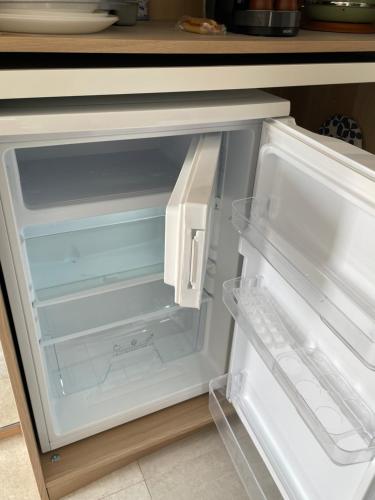 an empty refrigerator with its door open in a kitchen at Ty kaz : élégant, tout confort et bien situé in Névez