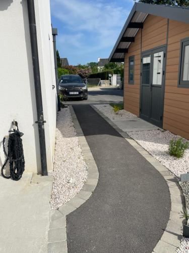 a walkway next to a building with a car parked at Ty kaz : élégant, tout confort et bien situé in Névez