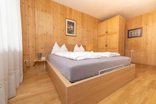 a bedroom with a bed with wooden walls and wooden floors at Ladurner Home in Brunico