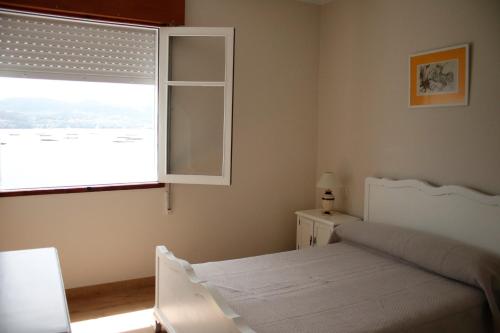 Casa sobre o mar A Ceboleira في راكسو: غرفة نوم بسرير ابيض ونافذة