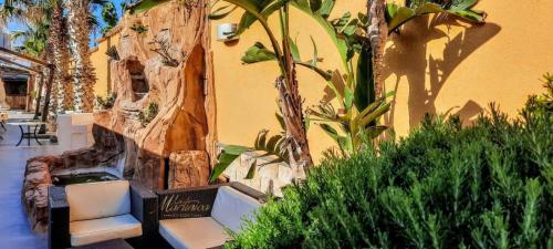 a patio with two chairs and trees and a building at Hotel La Martinica in Ficarazzi