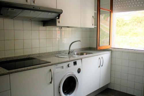 uma cozinha com uma máquina de lavar roupa e um lavatório em Casa sobre o mar A Ceboleira em Raxó