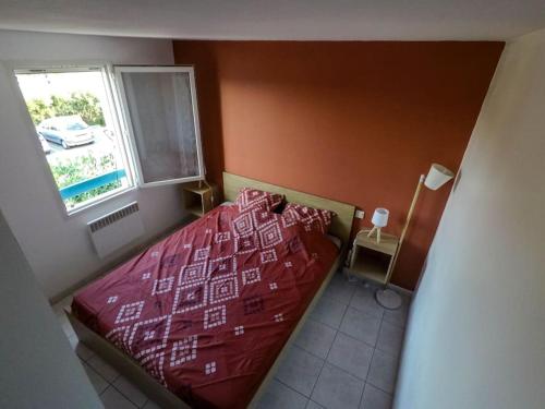 - une chambre avec un lit rouge et une fenêtre dans l'établissement Appartement refait à neuf à 500m de la plage, à Torreilles