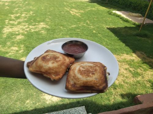 a plate with two pancakes and a bowl of sauce at Pari Resort with Nature View in Pushkar