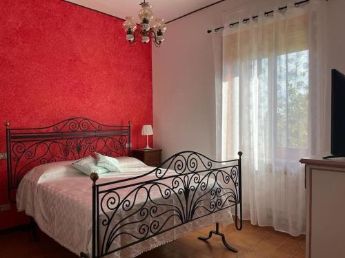 1 dormitorio con cama y pared roja en Dimora Falconi, en Arnesano