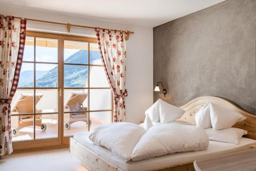 a bedroom with a bed and a large window at Hotel Kassian in Lagundo