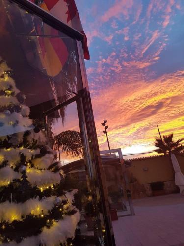 a christmas tree in front of a building with a sunset at Hotel La Martinica in Ficarazzi
