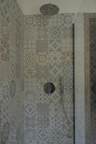 a shower with a glass door with a tile wall at Sikelìa Bed & Breakfast in Carini