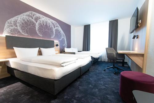 a hotel room with two beds and a desk at Taste Hotel Jettingen in Jettingen-Scheppach