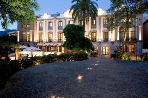 a large building with a palm tree in front of it at Gran Hotel Soller in Sóller