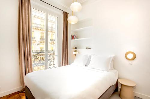 1 dormitorio con cama blanca y ventana en Quatre Septembre en París