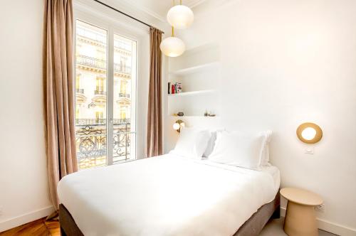une chambre avec un lit blanc et une fenêtre dans l'établissement Habitat Parisien - 2BR-2BA - AC - Balcony - Opéra, à Paris