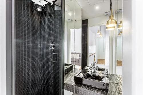 une salle de bain noire avec un lavabo et un miroir dans l'établissement Habitat Parisien - 2BR-2BA - AC - Balcony - Opéra, à Paris