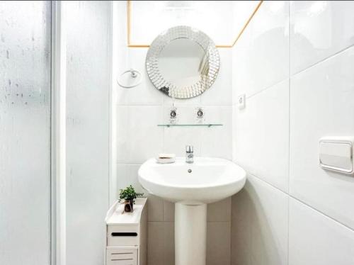 Baño blanco con lavabo y espejo en Stunning apartment at beach en Caldes d'Estrac