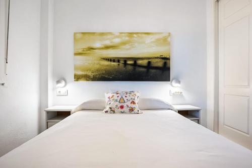 a bedroom with a white bed with a painting on the wall at Casa Vistas al Mar Bolonia 2 in Tarifa