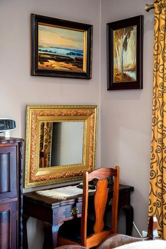a mirror on a wall with a desk and a chair at aHa Guest House in Sea View