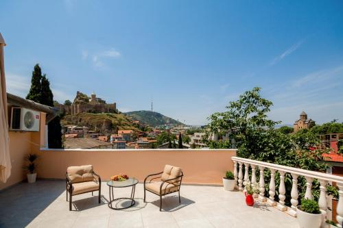 patio z 2 krzesłami i stołem na balkonie w obiekcie Gvino Minda w mieście Tbilisi City