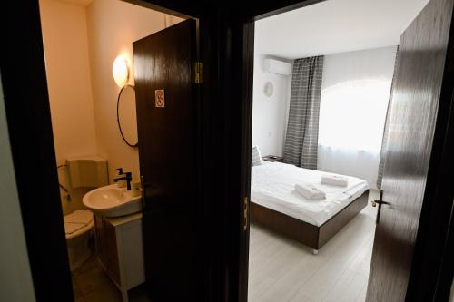 a small bathroom with a bed and a sink at Vila Medusa in Vama Veche