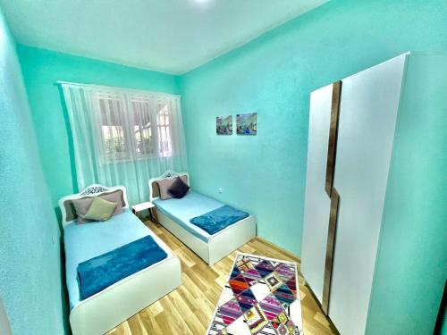 een blauwe kamer met 2 bedden en een koelkast bij Apartment-Rubin in Pristina