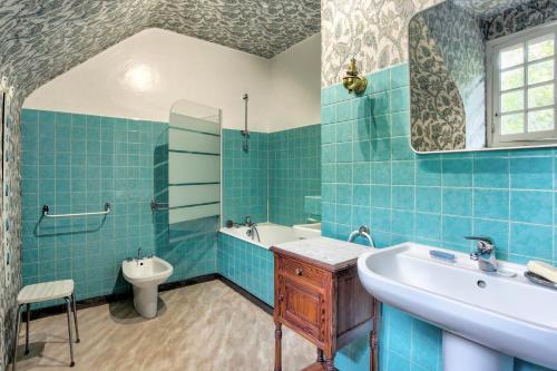 La salle de bains est pourvue de carrelage bleu, d'un lavabo et de toilettes. dans l'établissement La Grangerie - Charmante demeure typique, à Erquy