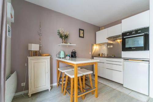 une cuisine avec une petite table et un comptoir dans l'établissement Alienor - Charmant appartement plein coeur dArcachon, à Arcachon