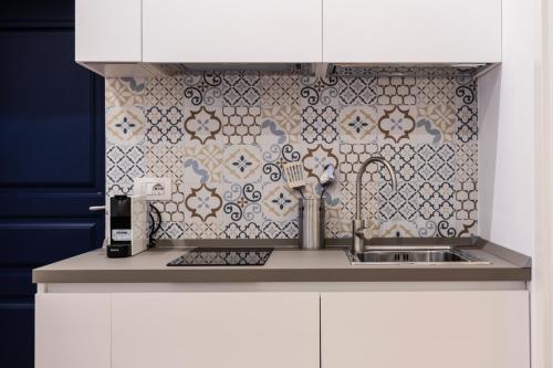 eine Küche mit einem Waschbecken und einer gefliesten Wand in der Unterkunft Eleonora Suites in Neapel