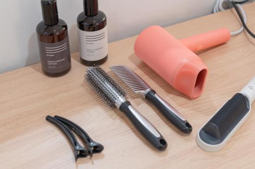a wooden table with two hair brushes and two bottles at Aank Hotel Cheonan Station 2nd in Cheonan