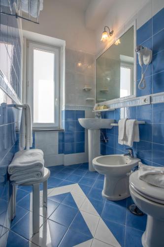 a blue tiled bathroom with a sink and a toilet at Hotel7Bello in Minori