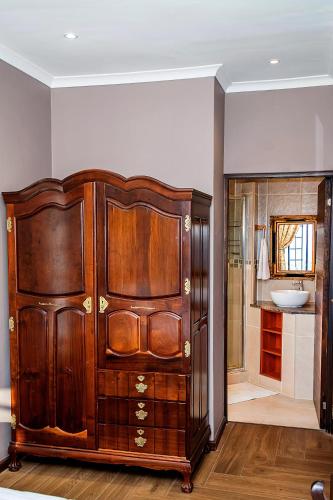 a large wooden cabinet in a bathroom with a sink at aHa Guest House in Sea View