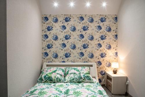 een kleine slaapkamer met een bed met blauwe bloemen aan de muur bij APARTAMENTY WYDMINY in Wydminy