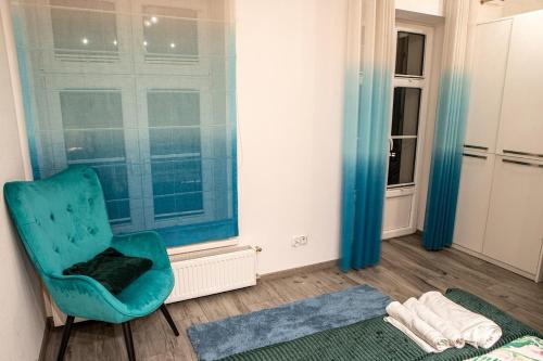 een kamer met een blauwe stoel en een raam bij APARTAMENTY WYDMINY in Wydminy