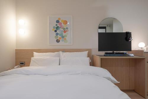 a bedroom with a bed with a computer on a desk at Aank Hotel Cheonan Station 2nd in Cheonan