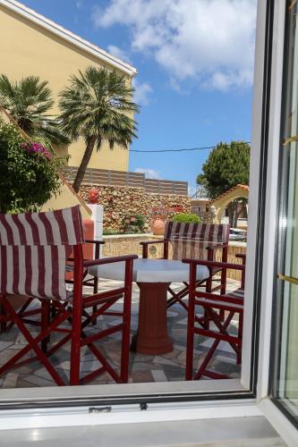 two chairs and a table on a patio with a window at Heaven Apartments in Agia Marina Nea Kydonias