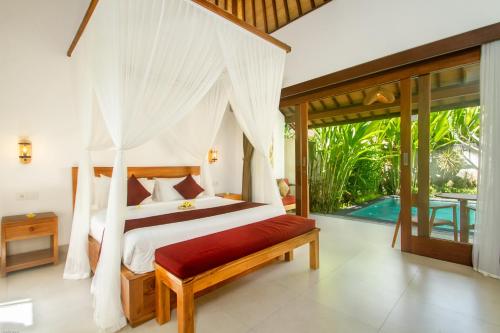 1 dormitorio con cama con dosel en una villa en de Metra Villa Ubud by Pramana Villas, en Ubud