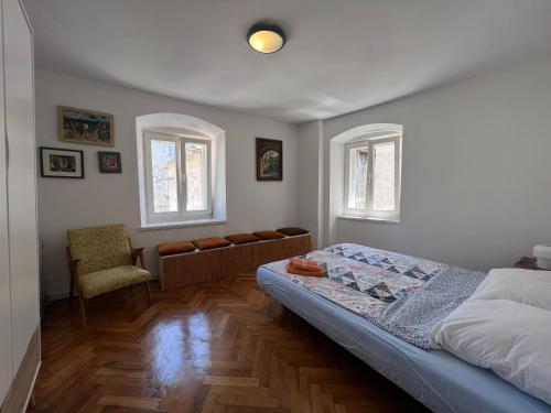 a bedroom with a bed and a chair and two windows at Split Old Town Apartments in Split
