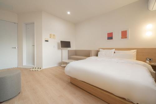 um quarto branco com uma cama grande e um sofá em The Hyoosik Aank Hotel Cheonan Station 2nd Branch em Cheonan