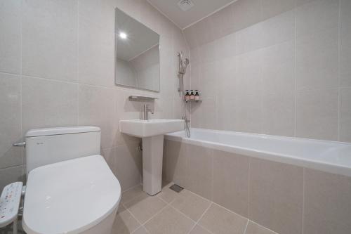 a bathroom with a toilet and a sink and a tub at Aank Hotel Cheonan Station 2nd in Cheonan