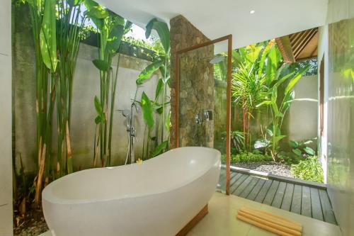 a bath tub in a bathroom with a garden at de Metra Villa Ubud by Pramana Villas in Ubud